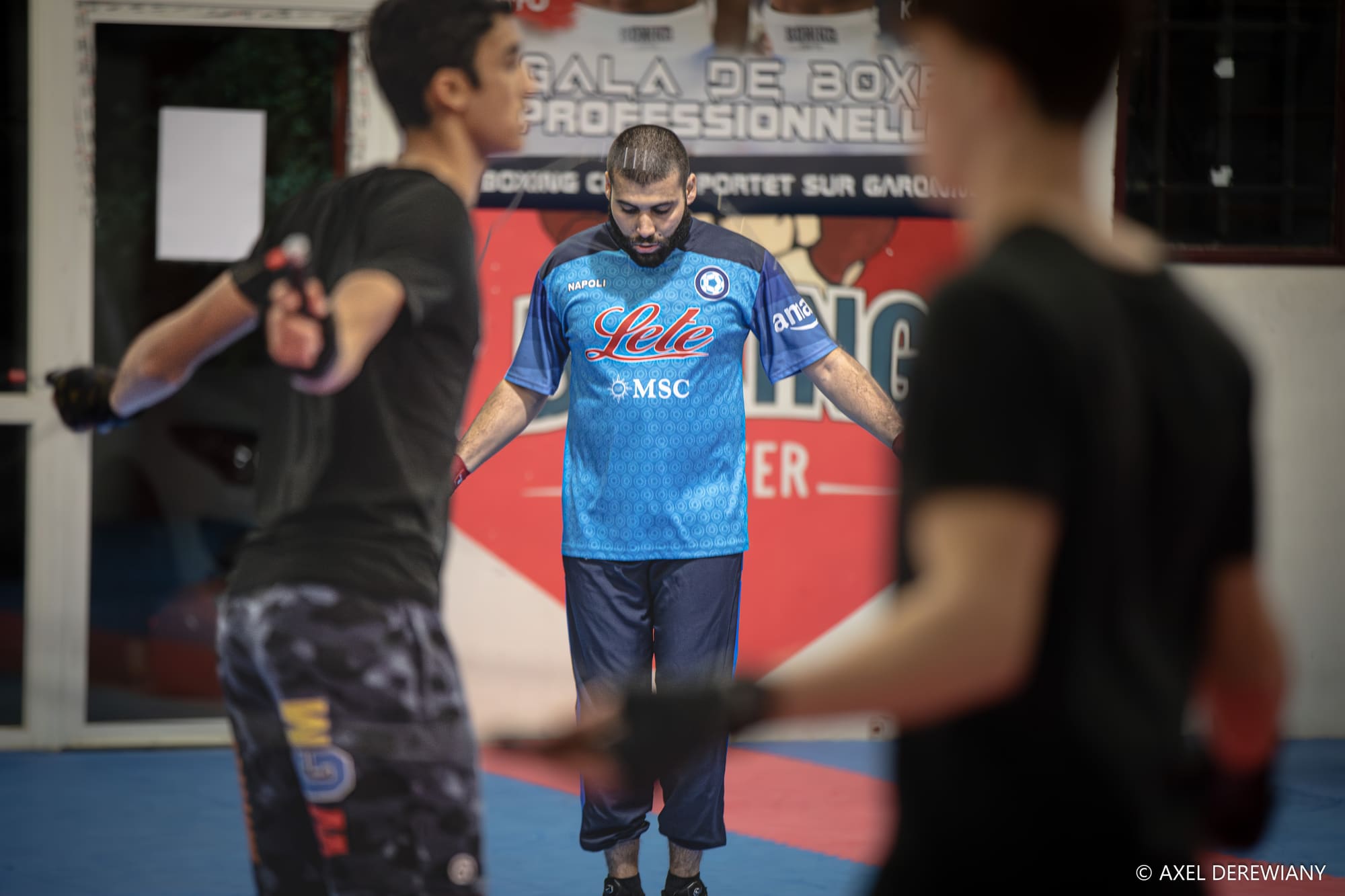 Deux pratiquants s’échauffent devant l’affiche d’un gala de boxe professionnel.